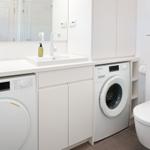 Badezimmer mit Waschmaschine, Spülmaschine und Toilette.