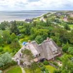 Dorfhaus mit Strohdach, umgeben von Grünflächen und nah am Strand.