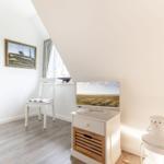 Zimmer mit Schrank, Stuhl, Fernseher und Laterne unter Dachschräge