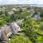 Dorf mit Strohdächern, Grünflächen und Meerblick