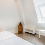 Schlafzimmer mit Dachschrägen, Bett, Stuhl und Fenster