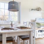 Dining room with table, chairs, and TV. Window with sailboat model.