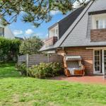 House with balcony, garden, and lounge chair. Terrace with table and chairs. Backyard with wooden fence.