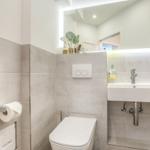 Bathroom with toilet, sink, and lit mirror.