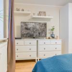 Bedroom with white wardrobe, TV, and plant on windowsill.