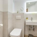 Bathroom with toilet, sink, and lit mirror