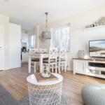 Living room with dining area, TV, and kitchen. Wooden floor and light walls.