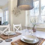Dining table for two, white table, chairs, window with sailboat.