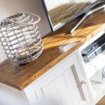 TV stand with wooden top, television, and decorative lantern.