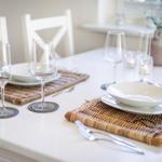 Table set with plates, glasses, and cutlery on woven placemats.