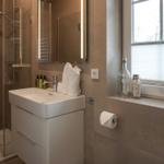 Badezimmer mit Dusche, Waschbecken und Fenster.