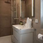 Badezimmer mit Dusche, Waschbecken und Spiegel.