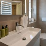 Badezimmer mit Waschbecken, Spiegel, Toilette und Handtüchern.