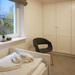 Schlafzimmer mit Blick auf Strand, Bett, Stuhl und Schrank.