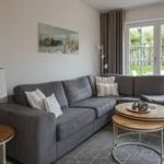 Wohnzimmer mit grauem Sofa, Holztisch und Blick auf Garten.
