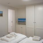Schlafzimmer mit Bett, Schränken und Fernseher. Wandbild zeigt Strand.