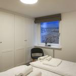 Schlafzimmer mit Bett, Kleiderschrank und Fenster mit Strandbild.