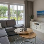 Wohnzimmer mit grauem Sofa, Holztisch und TV-Möbel.