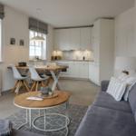 Wohnzimmer mit Sofa, Couchtisch und Essbereich. Küche im Hintergrund.