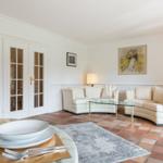 Wohn- und Essbereich mit weißen Sofas, Glas-Tisch und Terrakottaboden.