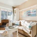 Living room with sofa, armchair, and windows to outdoor terrace.