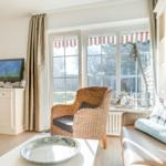 Living room with seating, TV, and windows overlooking the garden.