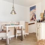 Dining area with table, two chairs, and wall art. TV on sideboard.