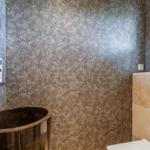 Badezimmer mit Steinwaschbecken und texturierten Wänden.