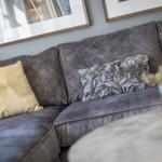 Grauer Sofa mit Kissen und Bildern an der Wand.