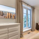Schlafzimmer mit Fernseher, Fenster und Schrank.