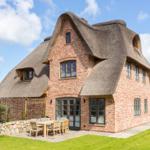 Haus mit strohgedecktem Dach und Holzterrasse im Garten