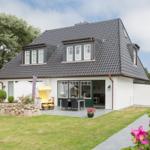 Wohnhaus mit Terrasse, Garten und Strandkorb.