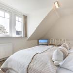 Schlafzimmer mit Dachschrägen, Fenster, Bett und Fernseher.