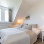 Schlafzimmer mit Dachschräge, Bett, Nachttisch und Fenster.