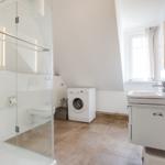 Badezimmer mit Dusche, Waschmaschine und Waschbecken