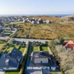 Aerial view of coastal village with houses and greenery near the sea.