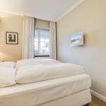 Bedroom with bed, window, and wall-mounted TV.