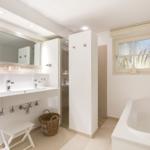 Bathroom with sink, shower, and bathtub. Window with view of grass.