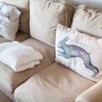 Beige sofa with cushions and knitted blanket