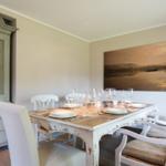 Dining room with table, chairs, and wall art. Wooden cabinet against wall.