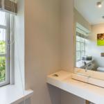 Bathroom with sink, mirror, and window overlooking garden.