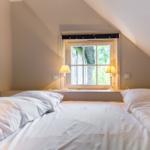 Bedroom with sloped ceiling, window, and two bedside tables with lamps.