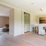 Dining room with table, chairs, and wall art. Passage to living area with sofa and terrace.