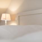 High-quality bed with white headboard and bedside lamp.