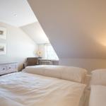 Room with two beds, window, lamp, and cabinet against the wall.