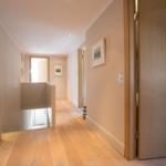 Hallway with wooden floor, doors, and wall pictures