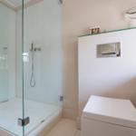 Shower with glass enclosure, toilet, and sink with mirror