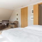 Bedroom with bed, chair, and view into the bathroom.