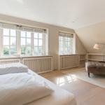 Bedroom with bed, windows, and seating area.