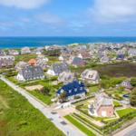 Aerial view of coastal village with traditional houses and ocean in background.